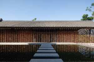 Minimalist wooden structure with water reflection, creating a serene and modern public art installation.