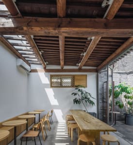 A cozy cafe interior featuring wooden furniture, including tables, chairs, and stools.