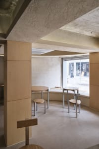 Cafe interior with minimalist design featuring concrete walls and wooden furniture.