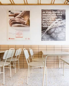 Modern restaurant interior featuring metal chairs and a tiled backsplash with concrete accents.