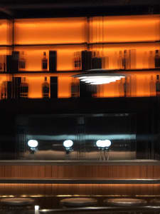 A modern bar interior featuring glass walls and warm lighting.
