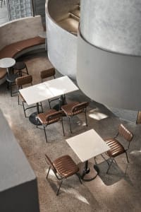 A modern cafe interior featuring concrete furniture and flooring.