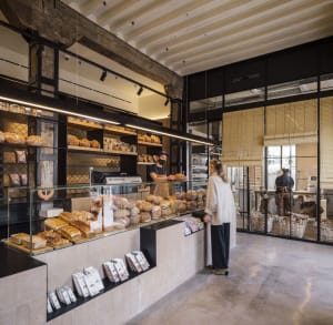 A modern retail shop with industrial design elements, featuring exposed concrete walls, wooden shelves, and glass display cas
