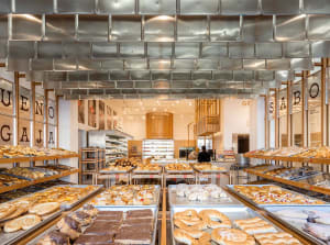 A modern bakery with metal walls and ceramic countertops filled with various baked goods.