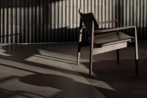 Modern chair with wooden staine in a dark, minimalist interior setting.