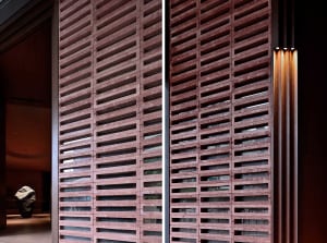 A close-up view of a contemporary interior featuring a brick barrier with horizontal slats and a warm, ambient lighting setup