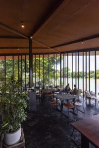 Modern restaurant interior with metal tables, glass walls, and black flooring