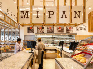 A modern retail counter in a bakery with a terrazzo countertop and shelves filled with baked goods.