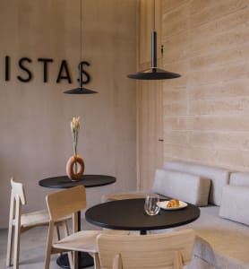 Modern coffee shop interior with wooden furniture, concrete walls, and minimalist design.