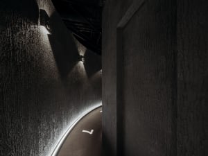 A minimalist interior with black concrete walls and a modern lamp.