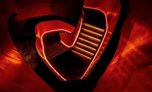 A modern, metallic staircase with red lighting, viewed from above.
