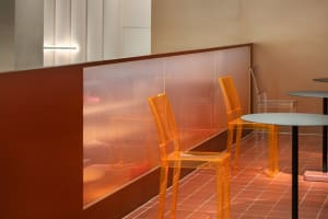 A photograph of a modern restaurant interior with transparent acrylic chairs and tables.