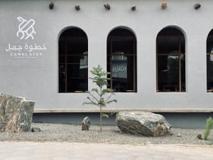 A modern coffee shop exterior featuring a minimalist design with concrete elements and large arch windows.