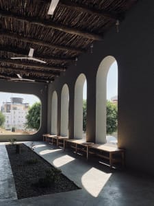 Architectural space with concrete columns, shadows, and seating area.