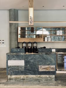An image of a modern coffee shop interior with a marble and concrete counter.