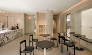 A modern coffee shop with minimalist design, featuring ceramic tiles and marble columns.