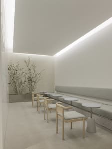 A minimalist coffee shop with concrete tables and seating area.
