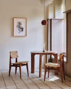 A modern dining room featuring wooden furniture, a round table, and two chairs with woven seats.