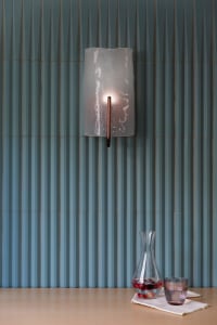 A modern interior design featuring a glass wall-mounted light fixture against a textured blue wall.