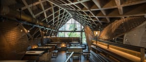 A modern restaurant interior featuring wood, metal, glass, and natural materials.