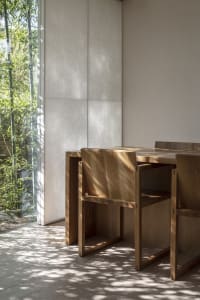 Minimalist interior design featuring a wooden table with a natural light-filled space, showcasing sleek lines and a monochrom
