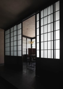A minimalist room featuring white windows, wooden flooring, and simple furniture.