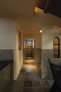 A hallway with tile flooring and concrete walls, showcasing spatial composition in interior design.