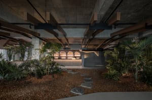 Industrial-style restaurant interior with concrete walls, wooden beams, and stone flooring.
