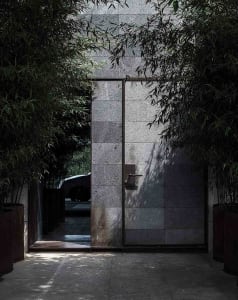 A modern exterior with concrete walls and lush foliage.
