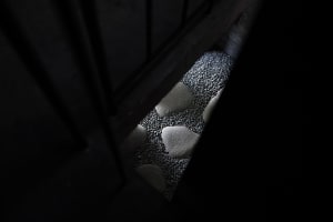 A close-up view of a concrete staircase with embedded gravel inserts, focusing on the texture and pattern created by the grav
