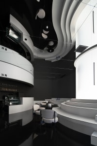 A modern restaurant interior with concrete walls, glass counter, and seating area.