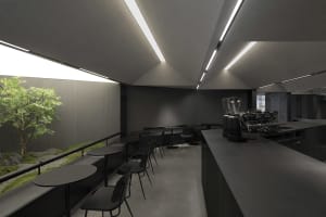 A minimalist coffee shop interior with concrete walls and black furniture.