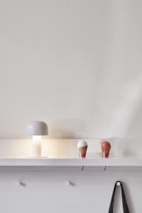 Minimalist white plastic shelf with a white table lamp and ice cream cones.