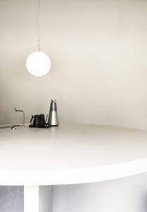 A minimalist kitchen counter featuring a white countertop and a single black kettle.