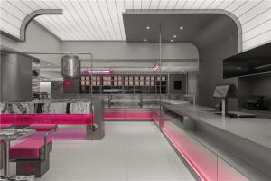 Interior view of a minimalist restaurant with metallic features, marble countertops, pink accents, and pink lighting fixtures