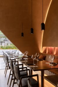 A modern restaurant interior with wooden tables, chairs, and walls.