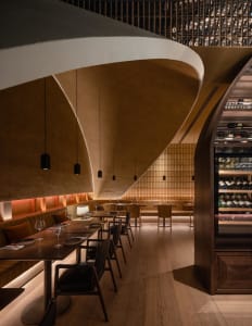 Modern restaurant interior featuring wooden tables, leather seating, and metal accents