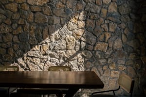 A wooden table in front of a stone wall in a restaurant setting.