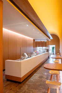 A modern coffee shop with a minimalist design, featuring a wooden countertop and seating area.