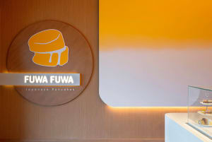 A modern, minimalist restaurant interior featuring wooden accents, glowing lights, and an acrylic pastry display counter.