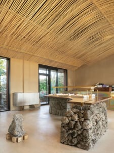A modern cafe with stone and concrete interior, showcasing wooden tables and seating.