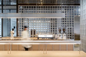 A modern industrial coffee shop counter with sleek metal and glass materials.