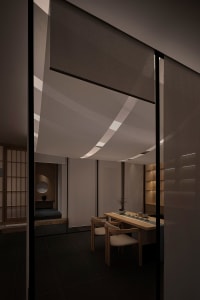 A minimalist tea room with wooden furniture and gray curtains hanging from the ceiling.
