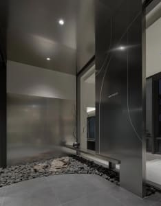 Modern minimalist lobby interior featuring black metal walls, gray stone ground, and glass elements.