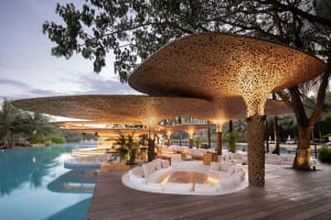 A contemporary bamboo architectural design featuring a poolside bar area with indoor and outdoor seating.