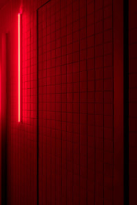 Minimalist red tiled interior design featuring a bright red neon light.