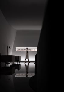 Person walking in a minimalist retail space with a concrete floor.