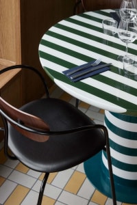A green-striped table with black chairs in a restaurant setting.