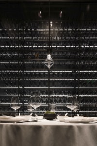 A modern industrial restaurant interior with metal racks, glassware, and minimalist design.
