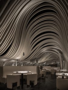 A minimalist white interior with a curved metal roof and illuminated by spotlights.